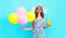 Fashion pretty smiling woman holds a fruit juice cup with an air colorful balloons