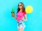 Fashion pretty smiling woman with pineapple sunglasses and yellow air balloon wearing a pink t-shirt over colorful blue