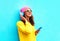 Fashion pretty sweet carefree girl listening to music in headphones with smartphone wearing a colorful pink hat yellow sunglasses