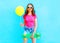 Fashion pretty woman holds yellow air balloon and skateboard having fun over colorful blue