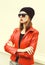 Fashion pretty woman with red lipstick wearing a rock leather jacket, sunglasses and black hat