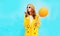 Fashion pretty woman sends an air kiss holds balloon in a yellow coat