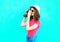 Fashion pretty woman taking picture wearing straw summer hat, sunglasses and vintage camera over colorful blue