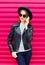 Fashion pretty woman talking on smartphone in rock black style over colorful pink