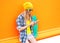 Fashion pretty woman using smartphone with skateboard over colorful orange