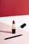 Fashion red lipstick and pencil top view composition. Beauty industry product concept. Glamorous makeup accessory close up on pink