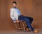 Fashion, serious and man in studio with trendy, stylish and classy suit on chair with confidence. Model, handsome and