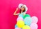 Fashion smiling young woman with an air colorful balloons is having fun on pink background