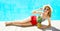 Fashion, summer holidays concept - woman lying with pineapple and sunglasses on a blue water pool