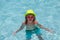 Fashion summer kids in hat and pink sunglasses. Child splashing in swimming pool.