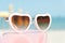 Fashion sunglasses heart shaped on pink stand with blue sea background