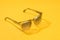 Fashion sunglasses in sunlight on summer pastel yellow background. Woman stylish eyeglasses for banner. Transparent