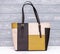 Fashion synthetic leather brown and yellow handbag on a wooden background. Eco leather.
