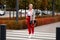 Fashion Trend for Autumn. Woman with short haircut walking across the street, wearing red pants, striped shirt, knitted cardigan