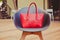 Fashion and trendy style large red handbag designer stands on a beautiful chair made of plastic in a summer cafe in the