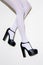 Fashion unrecognizable Model legs in white tights and black Lady shoes. Minimalist elegant details style. Retro vintage aesthetics