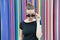 Fashion urban style concept. Lady mysterious face picking out of black eyeglasses in front of striped colorful wall in