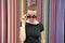 Fashion urban style concept. Lady mysterious face picking out of black eyeglasses in front of striped colorful wall in