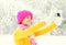 Fashion winter happy smiling young woman taking picture self portrait on smartphone over snowy trees wearing colorful knitted hat