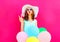 Fashion woman blowing lips holds an air colorful balloons on pink background