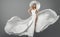 Fashion Woman in White Flying Dress and Summer Hat over Gray Studio Background. Elegant Bride in Wedding Gown. Beautiful Girl in