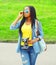 Fashion young african woman holds retro vintage camera wearing a jeans clothes and sunglasses in the city