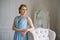 Fashion young beautiful woman in blue long dress, stands in living room leaning