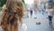 fashion young lady in jeans and stylish red shoes walks on urban street through crowd