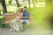 Fashion young teenage couple resting in a city park with drinks sitting on a bench on a sunny summer day