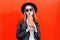 Fashion young woman drinks fresh fruit juice from cup in black rock style having fun over colorful red
