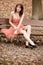 Fashion young woman in red dress relaxing in park on bench