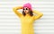 Fashion young woman wearing a knitted pink hat, yellow colorful sweater over white