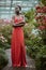 fashionable african american model in red dress with crossed arms posing in garden