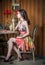 Fashionable attractive woman in multicolored dress sitting in restaurant. Beautiful brunette posing in elegant vintage scenery