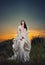 Fashionable beautiful young woman in white bridal long dress posing outdoor