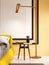 Fashionable bedside table in black with a standing floor lamp against a yellow wall in the background