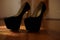 Fashionable black women shoes, golden shiny high heel. Brown parquet room