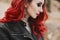 Fashionable close-up portrait of a model girl with red hair and trendy makeup in a leather jacket. Cropped portrait of a