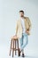 Fashionable confident man leaning on stool