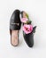 fashionable female black mule shoes with pink eustoma flowers on a white background.