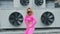 Fashionable funky dancer woman in pink sportswear is performing outdoor street dancing motion. Joyful summer female