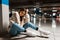 Fashionable girl listening to music in wireless headphones while sitting in the underground parking of shopping mall.