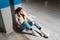 Fashionable girl listening to music in wireless headphones while sitting in the underground parking of shopping mall.