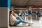 Fashionable girl listening to music in wireless headphones while sitting in the underground parking of shopping mall.