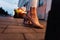 Fashionable girl in stylish beige summer shoes stands on a tile in the city in the evening,  close up