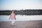 The fashionable girl in white trousers near the lake. The child costs barefoot on sand