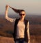 Fashionable,glamorous model stand on hills and held ponytail.Attractive,beautiful girl with sunglasses look at sunset.