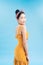 Fashionable graceful Young woman posing on blue background. Romantic adorable girl in polka dot yellow dress