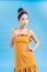 Fashionable graceful Young woman posing on blue background. Romantic adorable girl in polka dot yellow dress