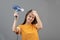 Fashionable hairstyle in a beauty salon. Young caucasian woman dries hair with a hairdryer on gray background, smiling